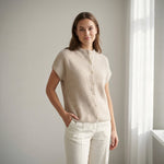 Model i beige vest i ribstrik med knapper foran, stylet med hvide bukser