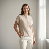 Model i beige vest i ribstrik med knapper foran, stylet med hvide bukser