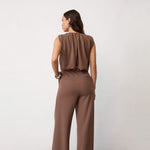 Model i brun jumpsuit set bagfra med læg i ryggen og lommer bagpå