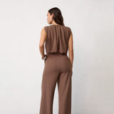Model i brun jumpsuit set bagfra med læg i ryggen og lommer bagpå