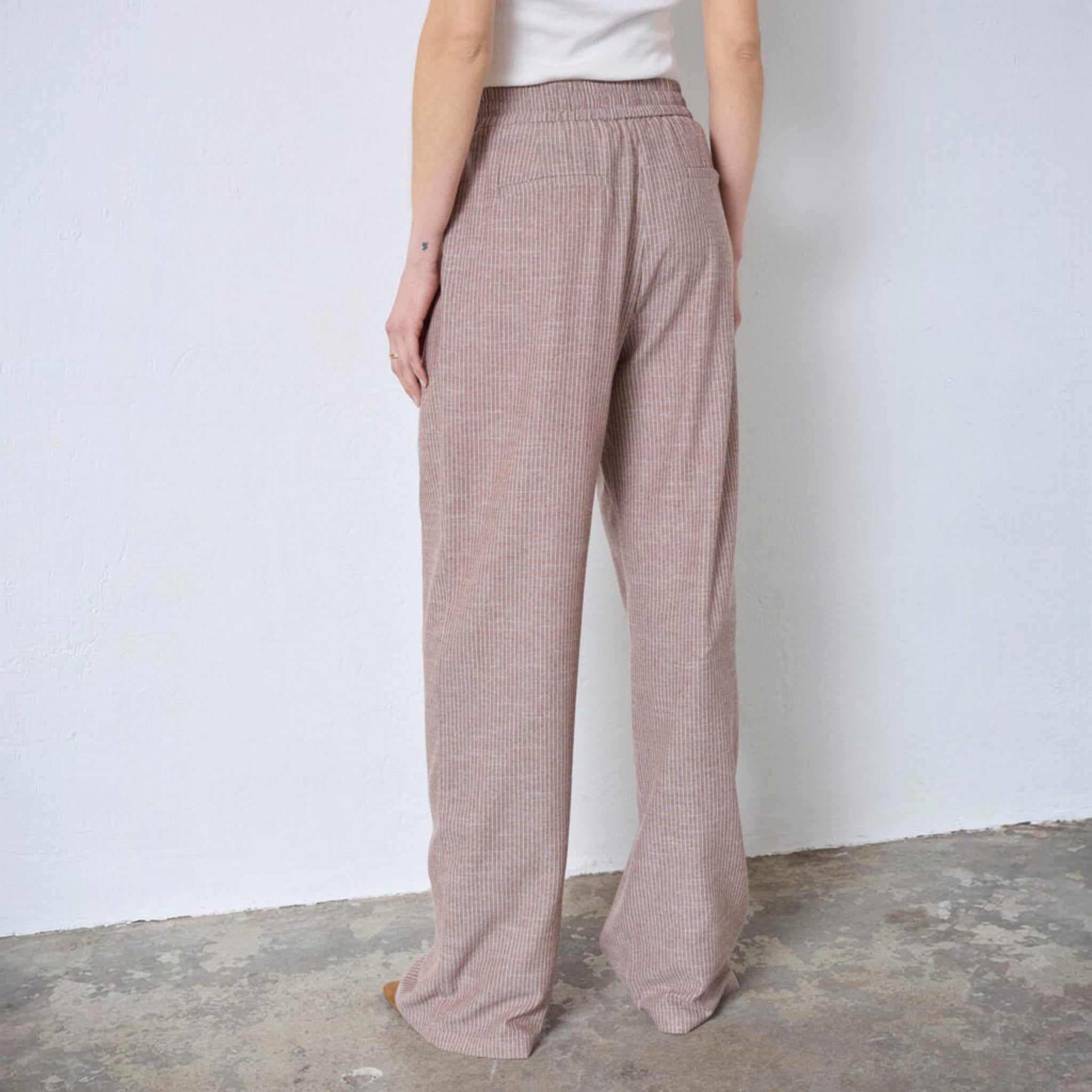 Model i brune nålestribede wide leg bukser, set bagfra