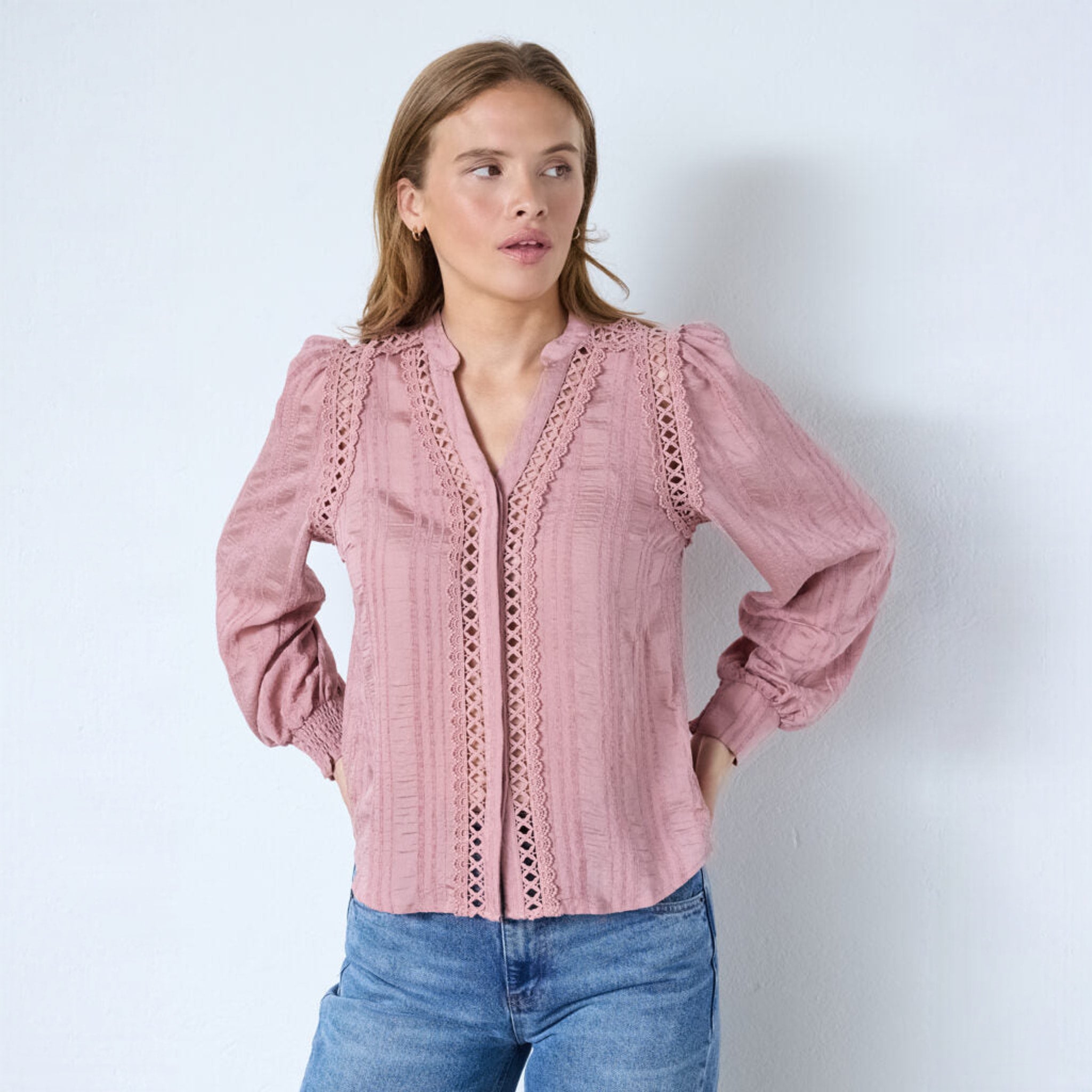 Pink skjorte med blondebånd, V-hals og puffede skuldre set forfra på model i jeans