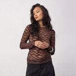 Model i brun bluse med prikker og rund hals sammen med sorte jeans set forfra