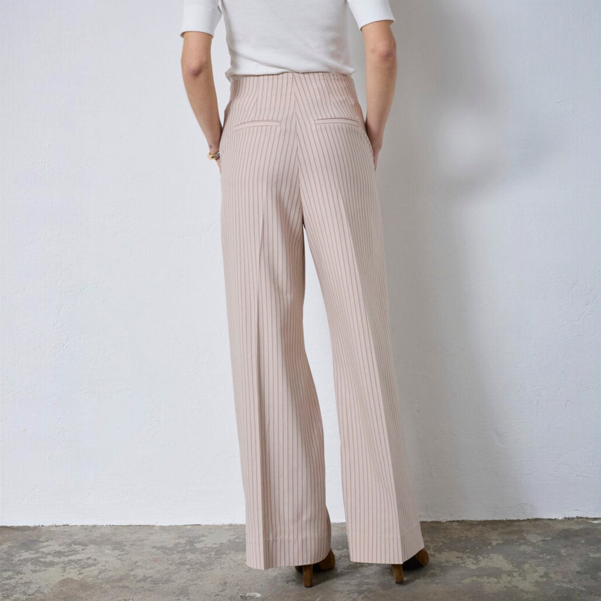 Model set bagfra i beige nålestribede wide leg bukser med lommer bagpå og pressefolder