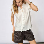 Model i hvid top med flæser ved halsudskæring og forstykke, stylet med brune shorts