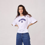 Model i hvid t-shirt med navy Co'Couture-logo, stylet med blå jeans