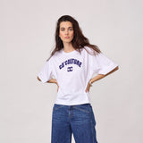 Model i hvid t-shirt med navy Co'Couture-logo, stylet med blå jeans