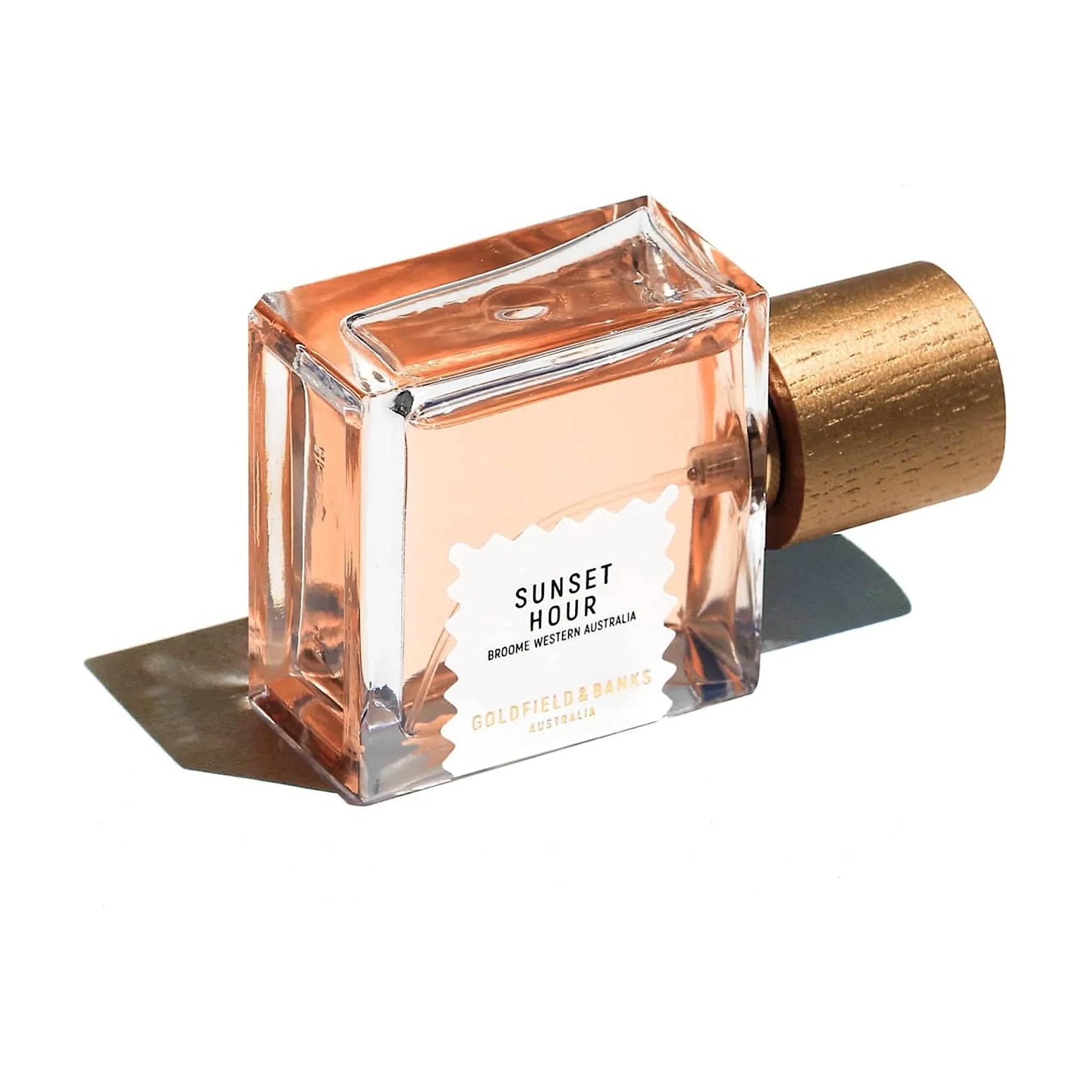 Sunset Hour parfume 50 ml liggende på siden, set skråt ovenfra med etiket og låg med træstruktur