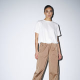 Model i hvid Karoline t-shirt fra Gossia stylet med beige bukser og sorte støvler
