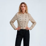 Model med hænderne i siden i beige Kelly Jacket fra Gossia og sorte bukser med læg