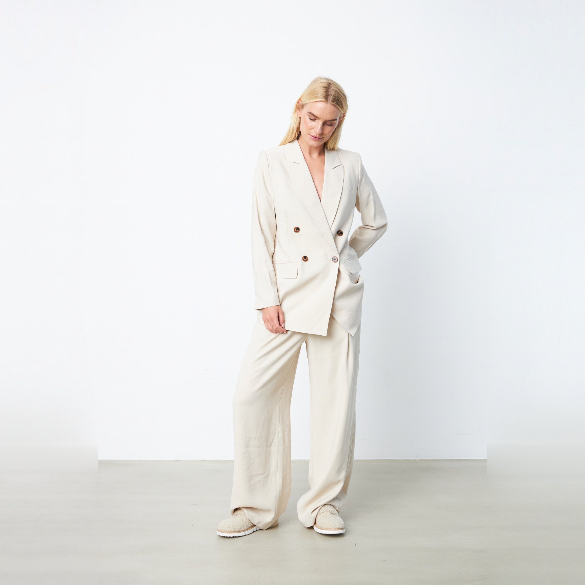 Model i beige dobbeltradet blazer fra Gossia i farven Sand stylet med lyse vide bukser