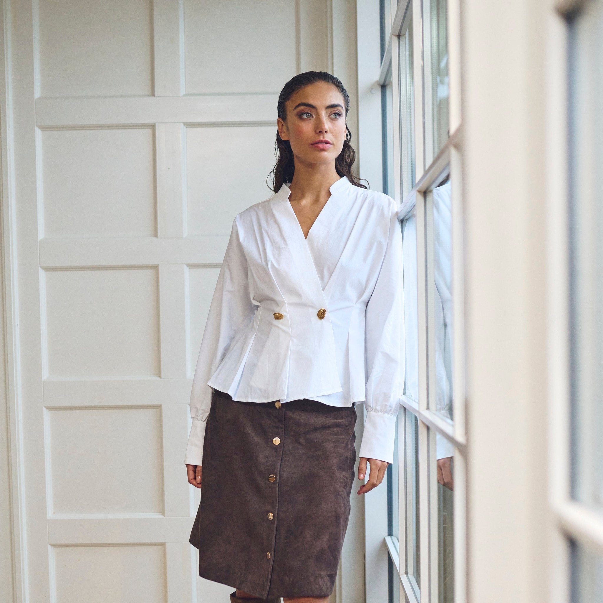 Model i hvid peplum bluse fra Gossia stylet med brun nederdel og høje støvler, hele figuren