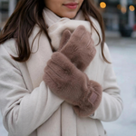 Model med beige handsker i fluffy pelslook i farven Taupe holdt op foran en lys frakke og halstørklæde