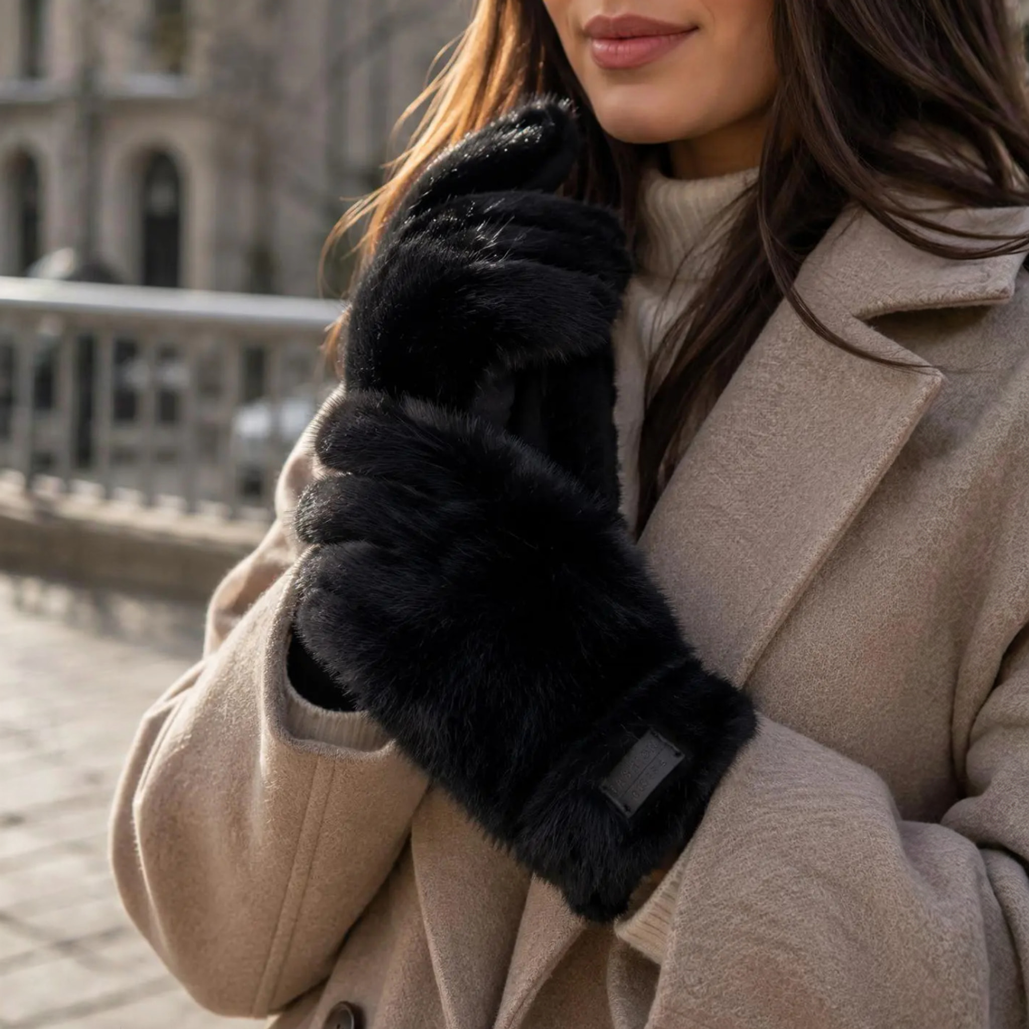 Model med sorte handsker i pelslook og mærke på manchetten, stylet med beige frakke og rullekrave