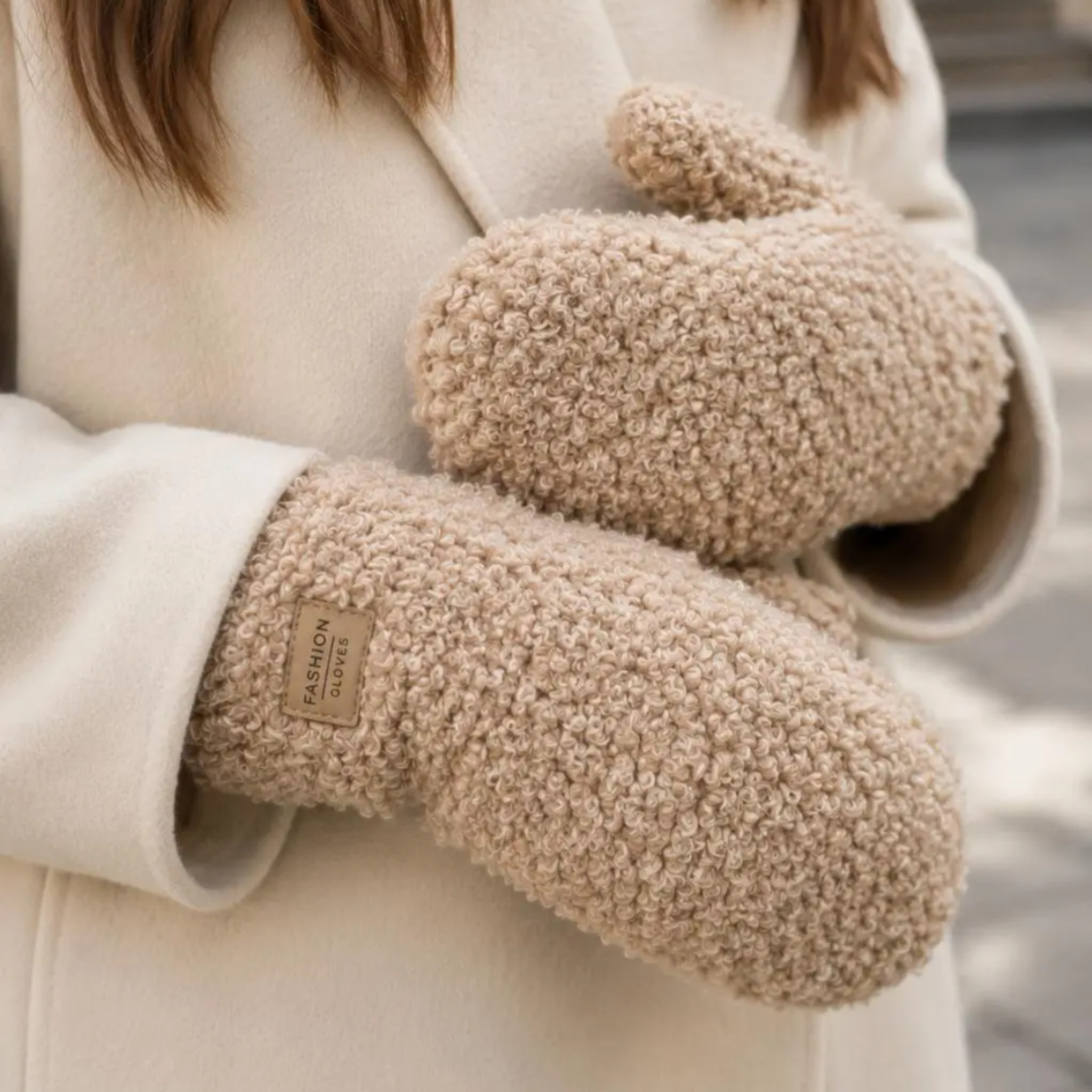 Model i lys frakke med beige handsker i teddy-look, tæt på hænderne