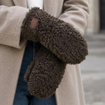 Model med brune handsker i teddy-look i farven Cafe, stylet med beige frakke, hvid strik og jeans
