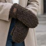 Model med brune handsker i teddy-look i farven Cafe, stylet med beige frakke, hvid strik og jeans