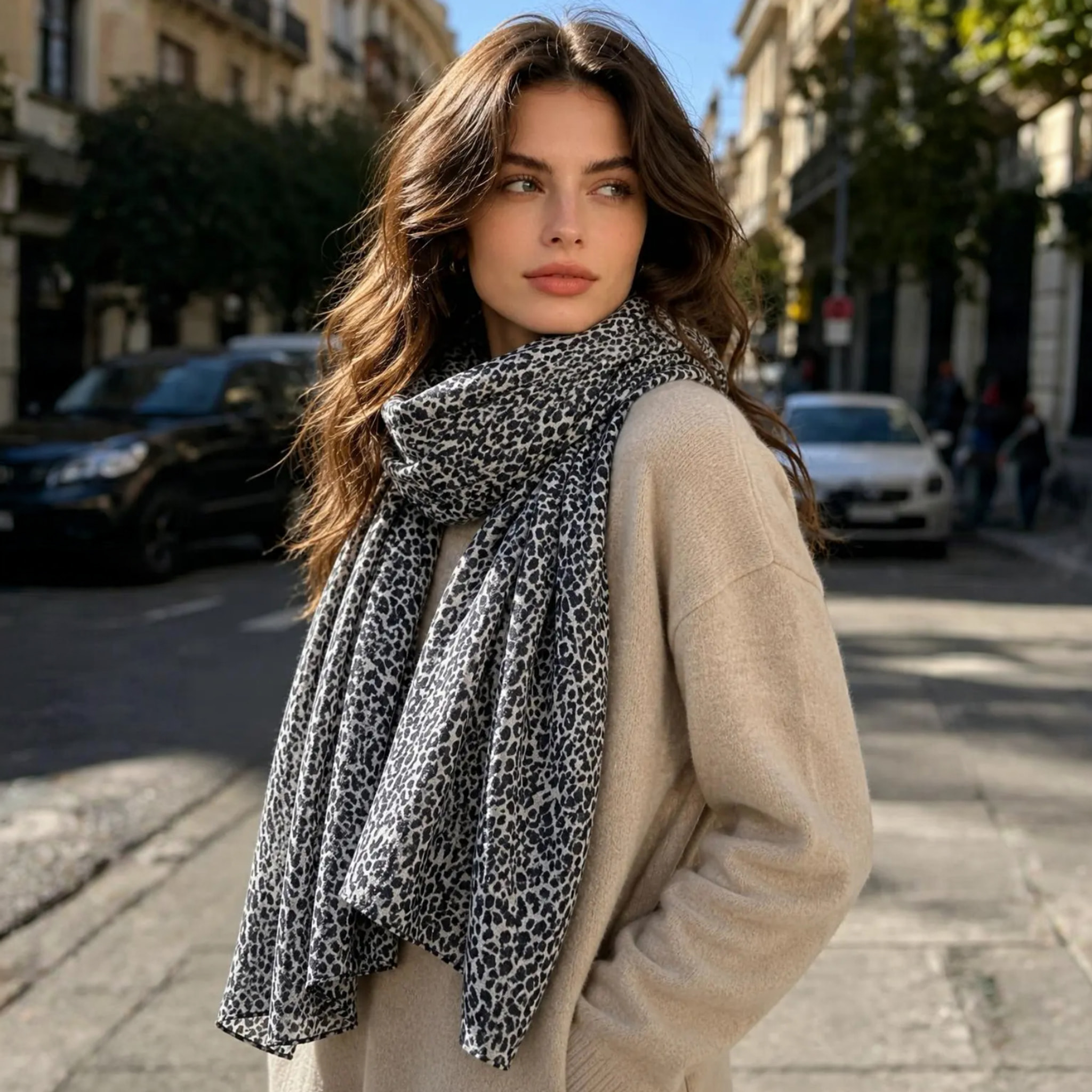 Model med gråt tørklæde med leopardprint slået løst om halsen over en beige overdel på en gade