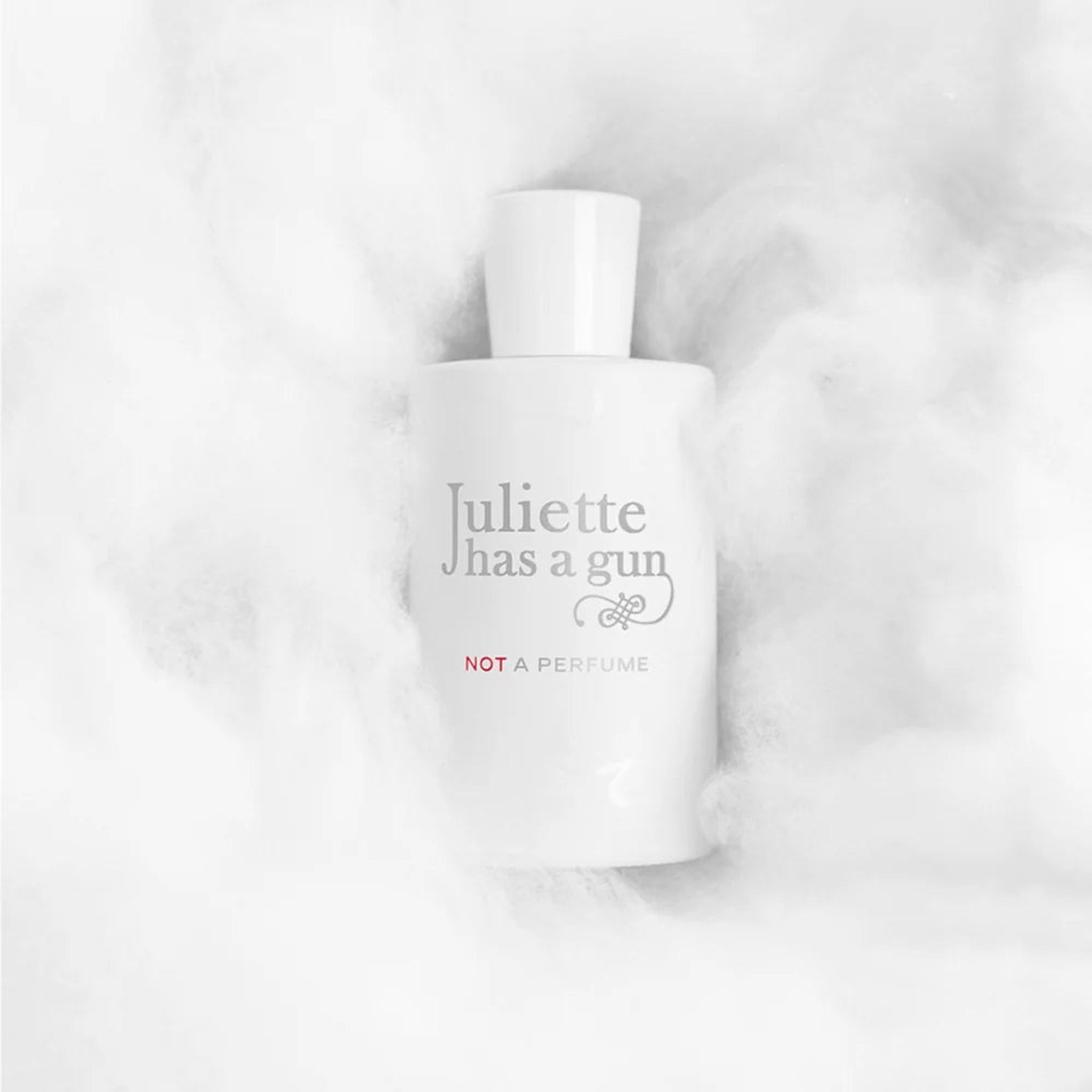 Hvid parfumeflaske Not A Perfume fra Juliette Has a Gun liggende i hvide, bløde fibre