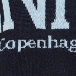 Nærbillede af strikket lyseblå Copenhagen-tekst på navy strik fra Marta du Chateau