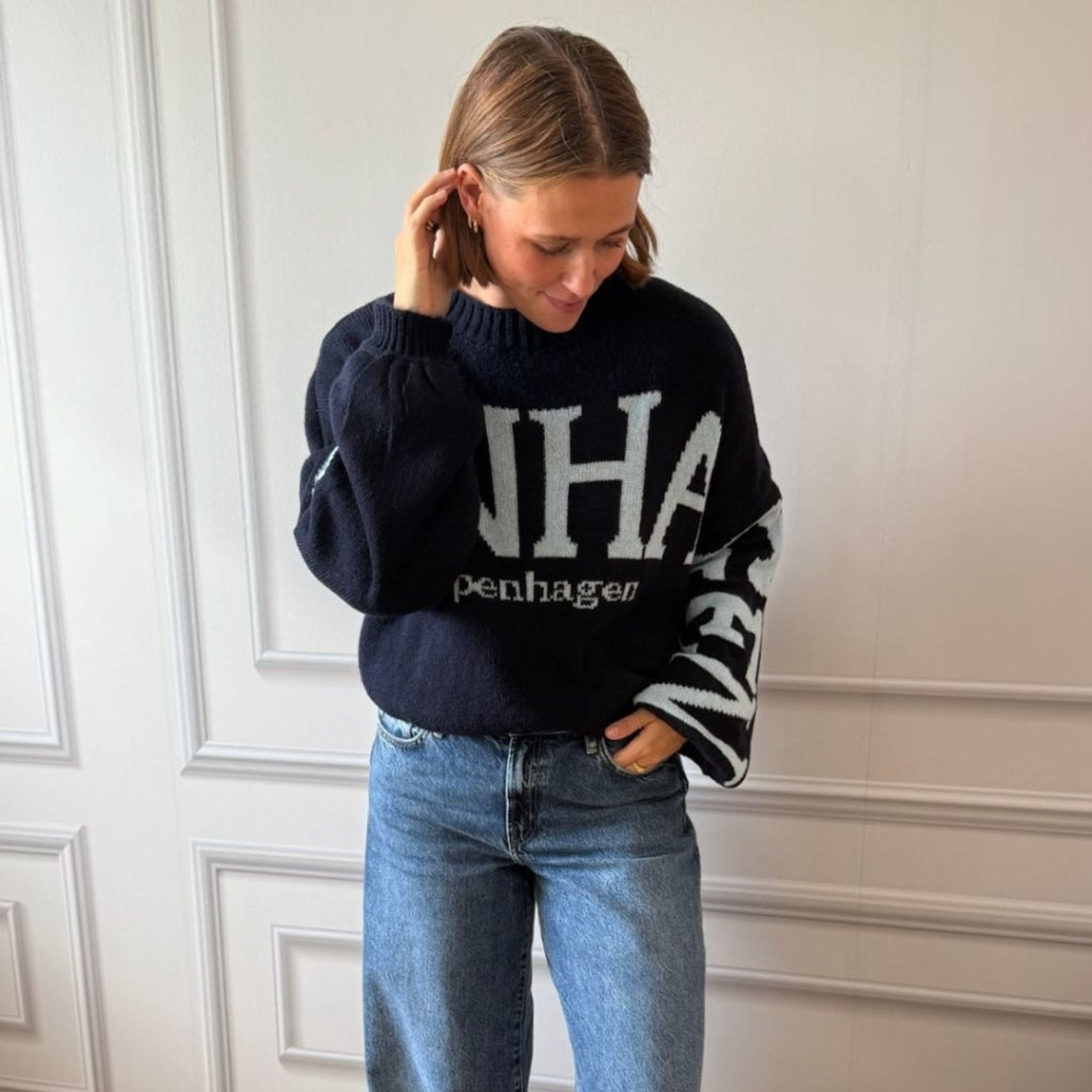 Model i navy oversize strik med lyseblå bogstaver stylet med blå jeans