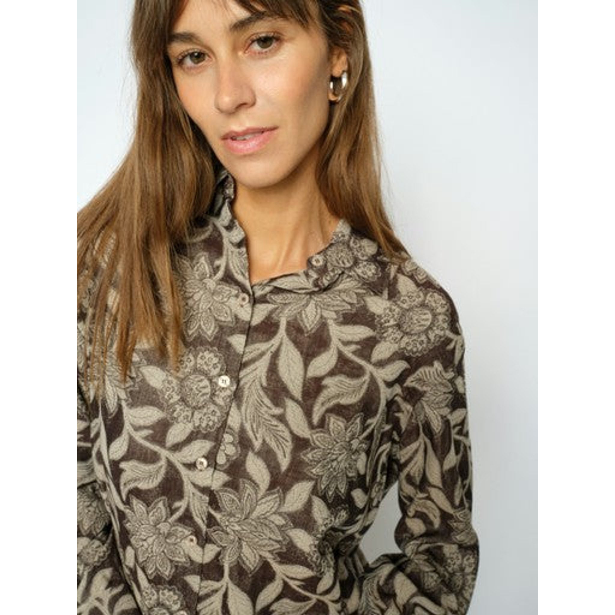 Tæt på kraven og knapperne på brun skjorte med blomsterprint båret af model