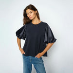 Model i navy bluse med puffede satinærmer stylet med lyse jeans, set forfra