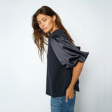 Model i navy bluse set fra siden med fokus på det puffede ærme i blank satin