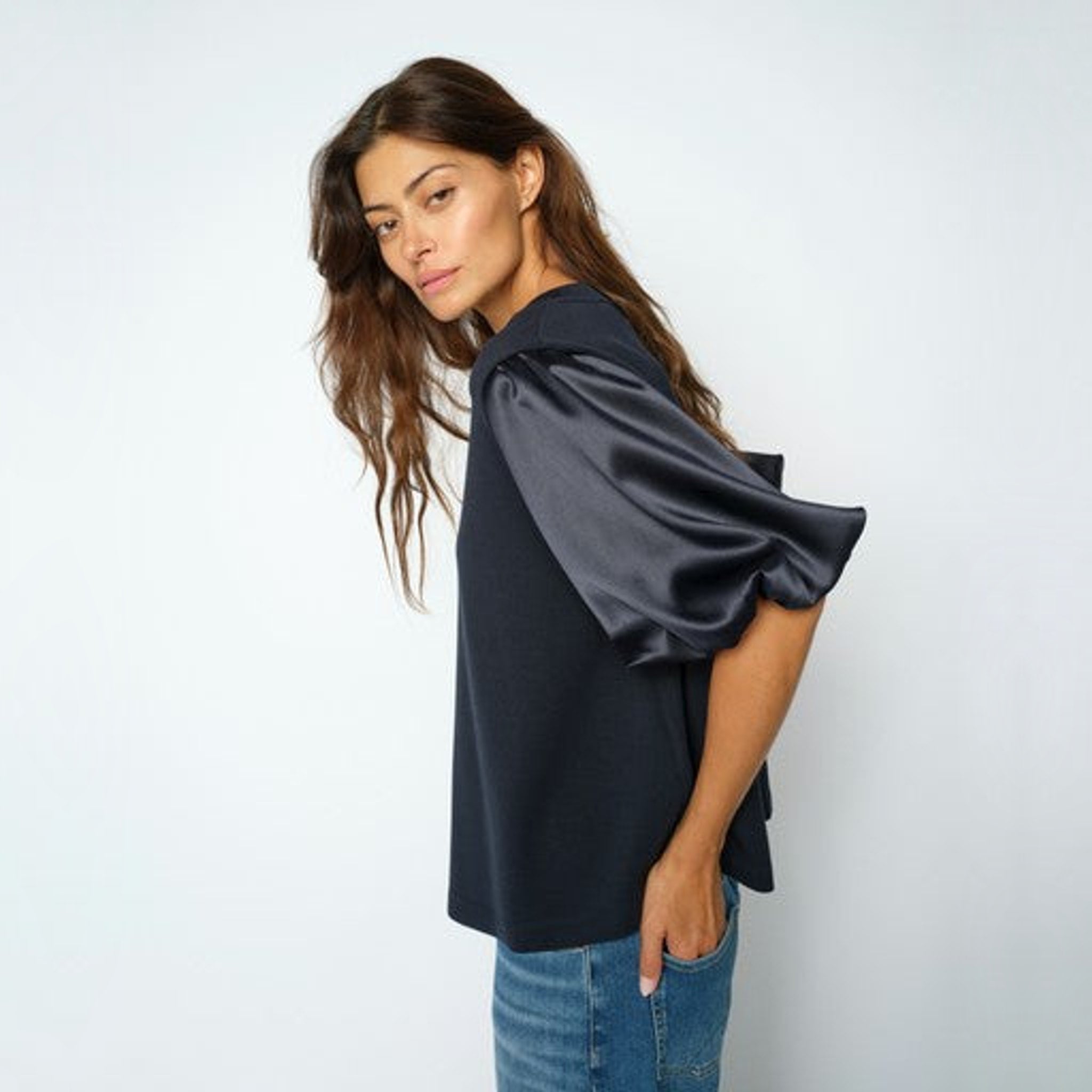 Model i navy bluse set fra siden med fokus på det puffede ærme i blank satin