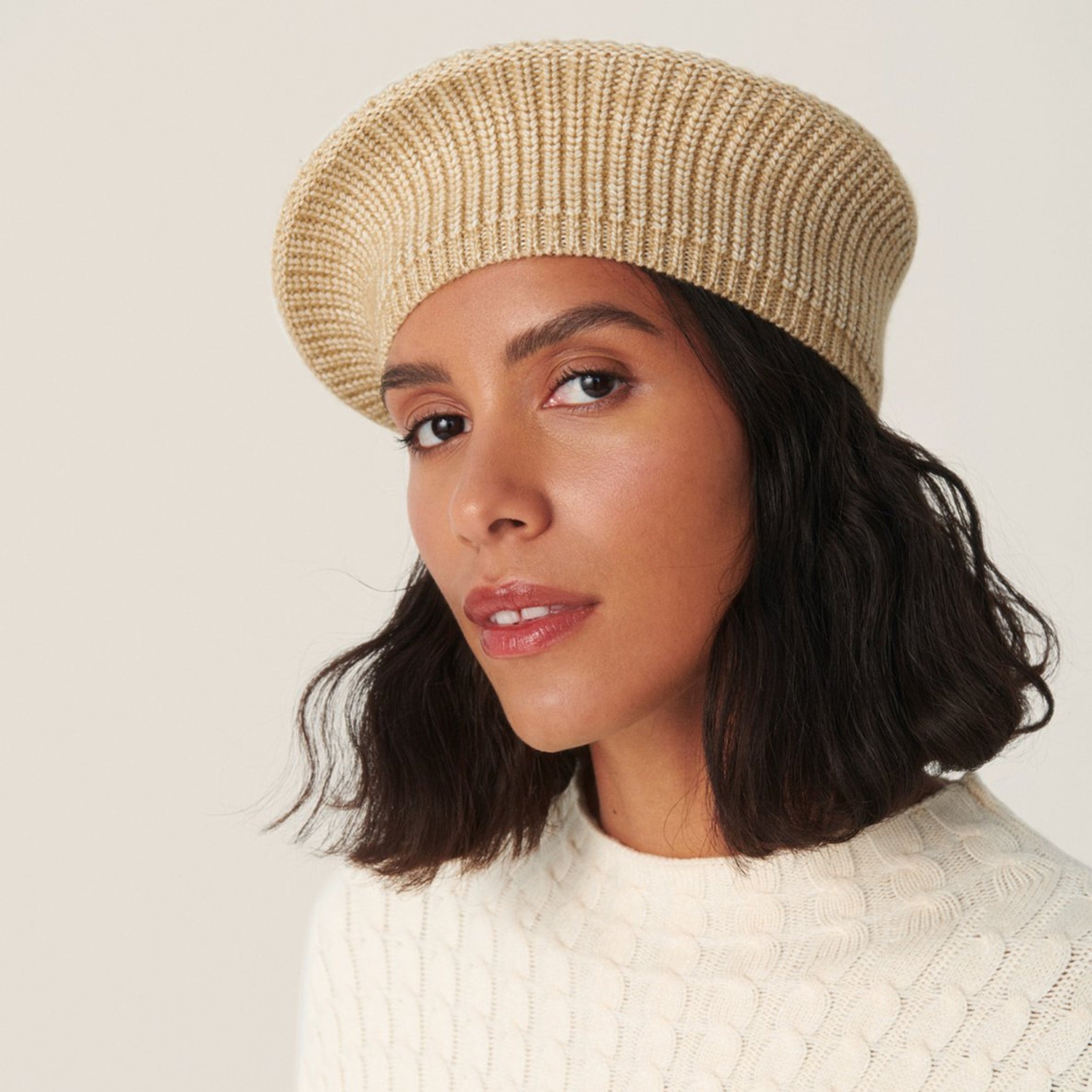 Model med beige strikket hat i baretform fra MSCH Copenhagen og cremefarvet strik