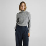 Model i grå pullover med høj rullekrave stylet med mørkeblå bukser med vide ben