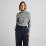 Model i grå pullover med høj rullekrave stylet med mørkeblå bukser med vide ben