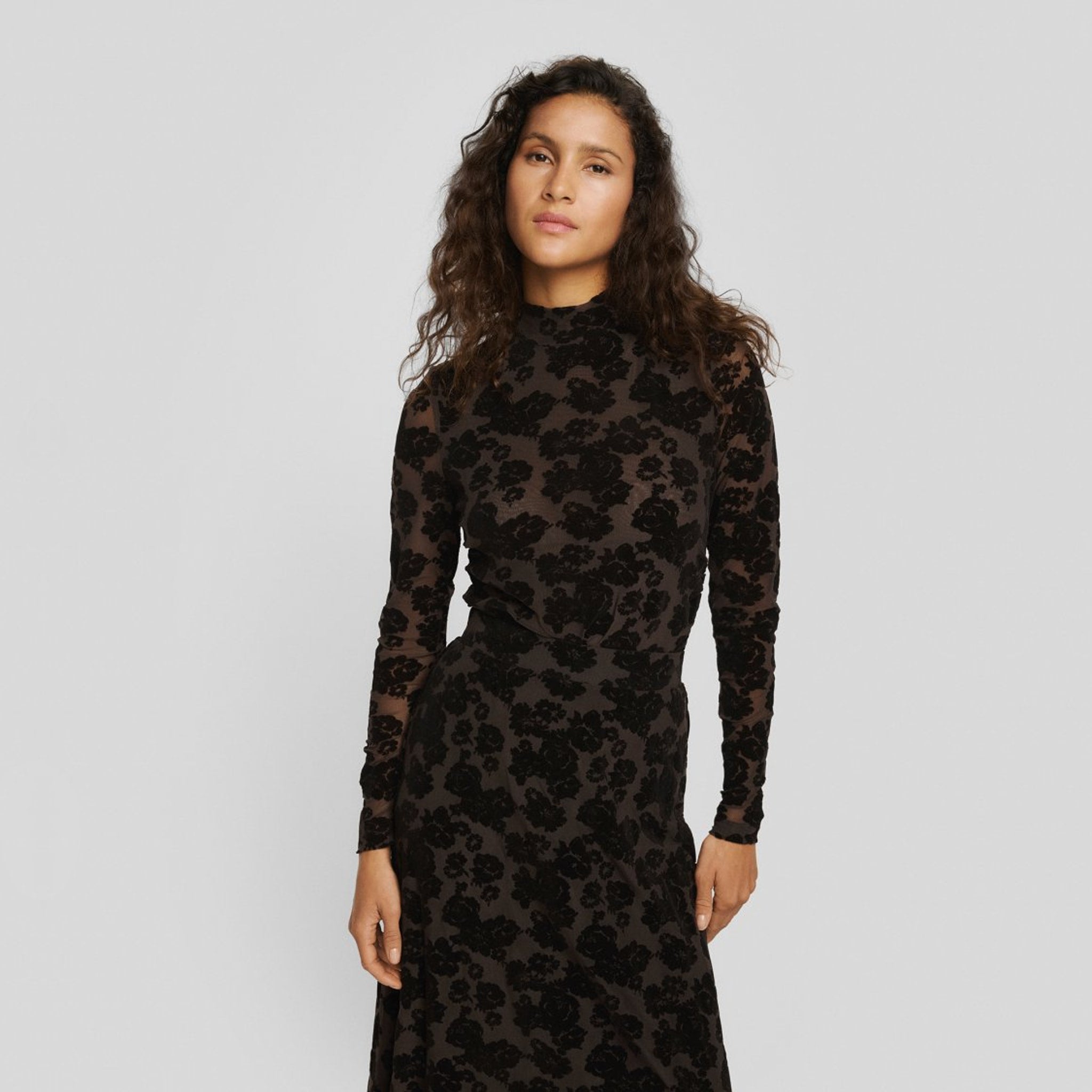 Model i tætsiddende brun mesh top med blomstret flock print og rullekrave