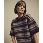 Model i kortærmet stribet pullover i lilla og grå strik med rund hals, tæt på