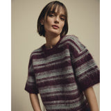 Model i kortærmet stribet pullover i lilla og grå strik med rund hals, tæt på