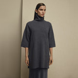 Model i lang navy pullover med rullekrave og sænkede skuldre set forfra over lang nederdel