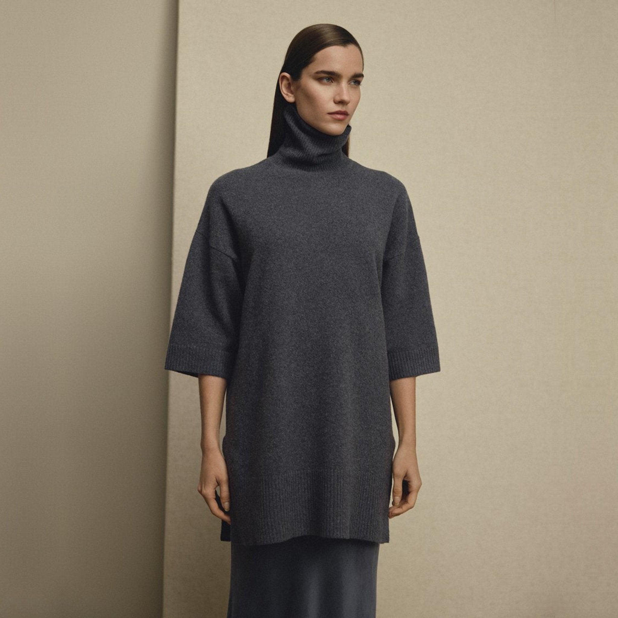 Model i lang navy pullover med rullekrave og sænkede skuldre set forfra over lang nederdel
