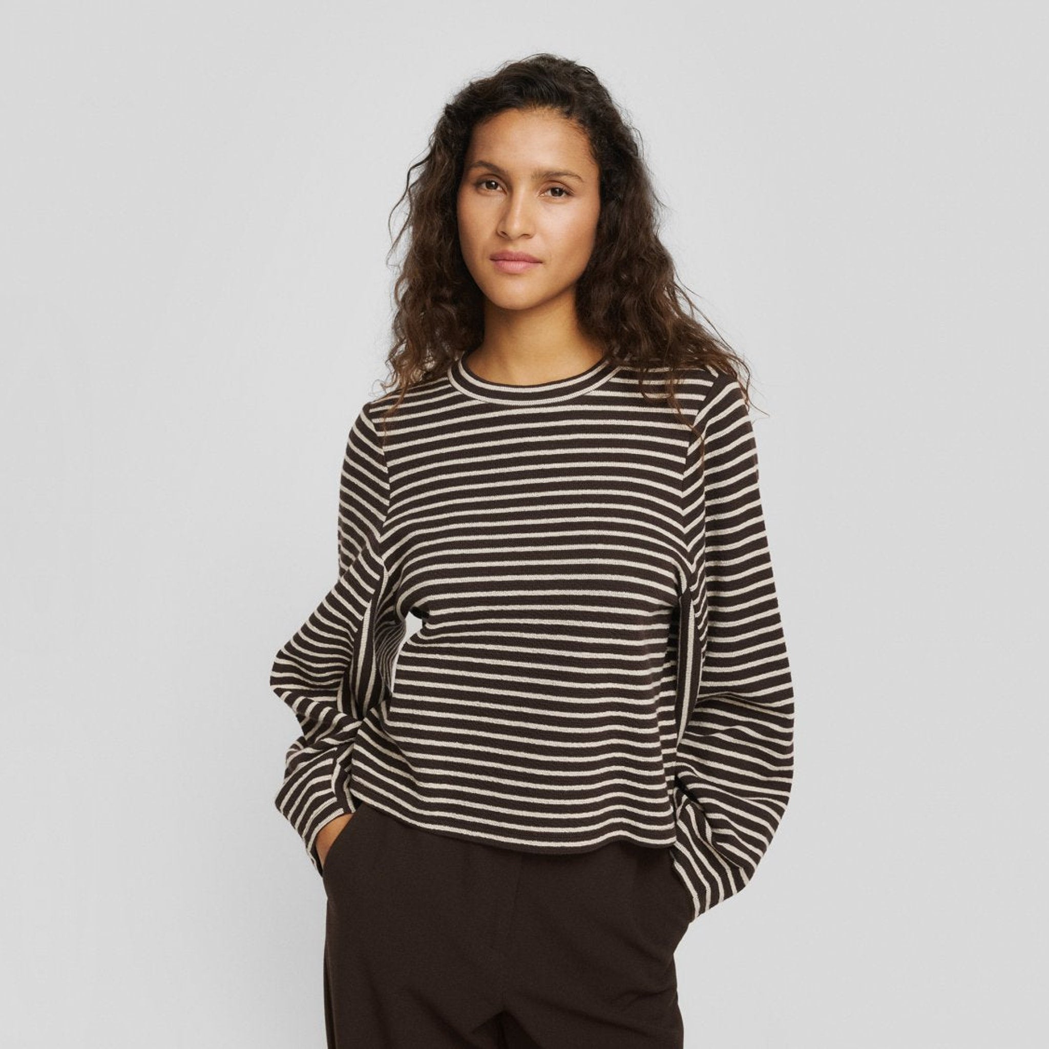 Model i brun og beige stribet sweatshirt med vide ærmer og brune bukser