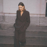 Model i brune wide leg bukser stylet med en matchende brun blazer og sorte støvler