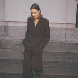 Model i brune wide leg bukser stylet med en matchende brun blazer og sorte støvler