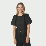 Smilende model i sort jakke med pufærmer og mandarinlukning set forfra