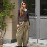 Model i grønne Bernie Pants bukser med løst snit stylet med brun cardigan foran en dør