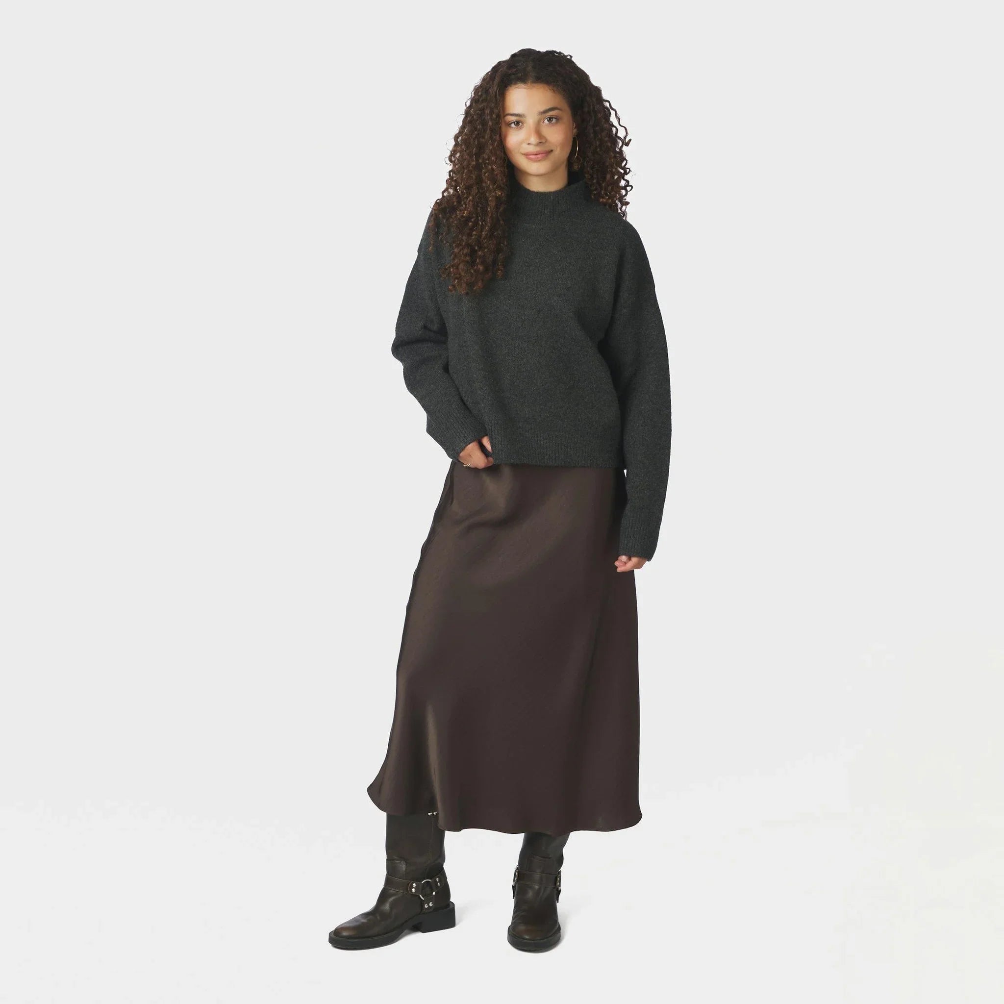 Model i brun satin nederdel i midilængde stylet med mørkegrå strik og sorte boots
