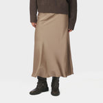 Model i brun midi nederdel i satin i farven Dark Taupe, set forfra med mørkebrun strik og støvler