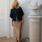 Model i brun midi nederdel i satin med navy cardigan og sorte pumps, helfigur