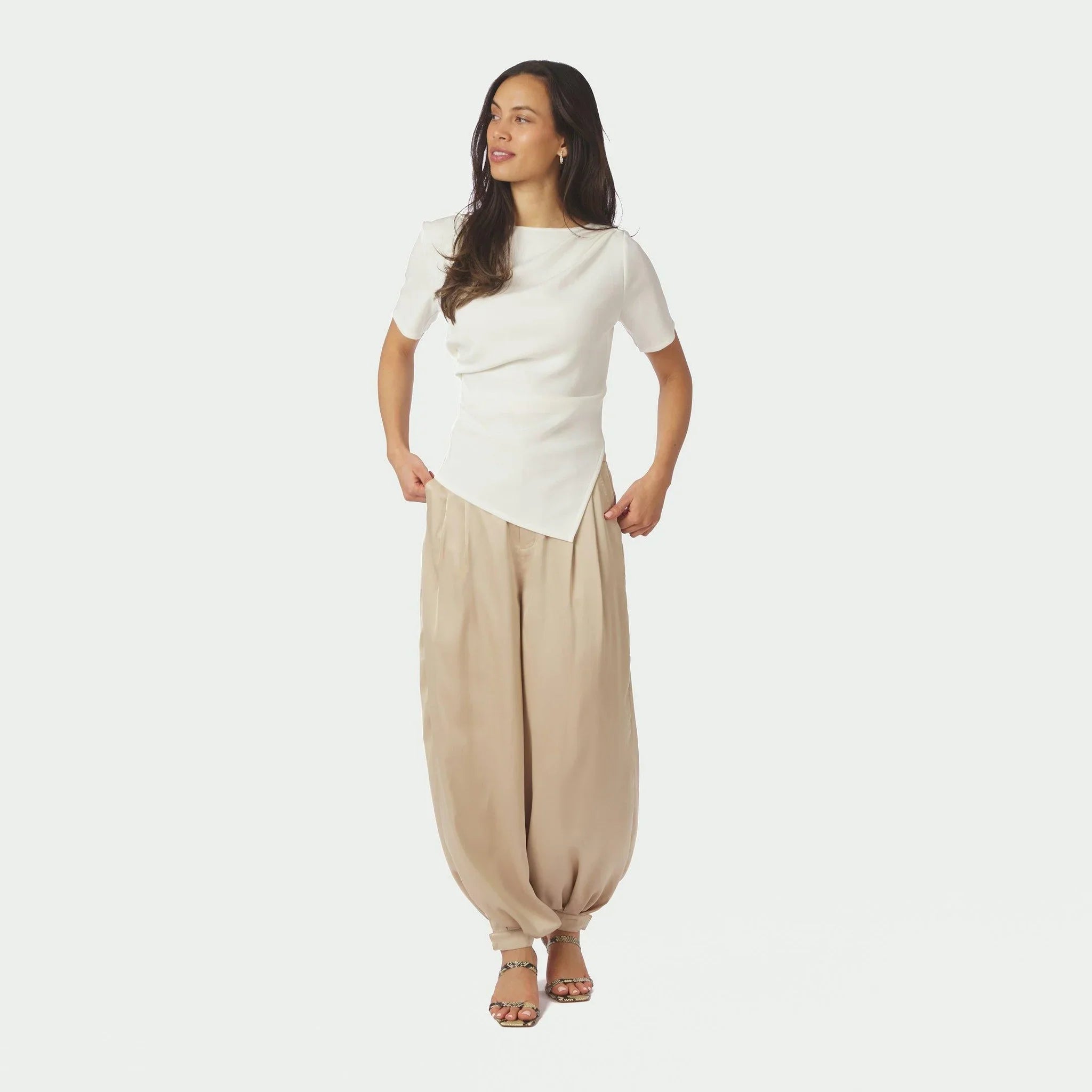 Model i hel figur i beige ballonbukser i satin i farven Dark Sand