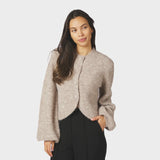 Model i beige fluffy cardigan med knapper foran og sorte bukser, set forfra