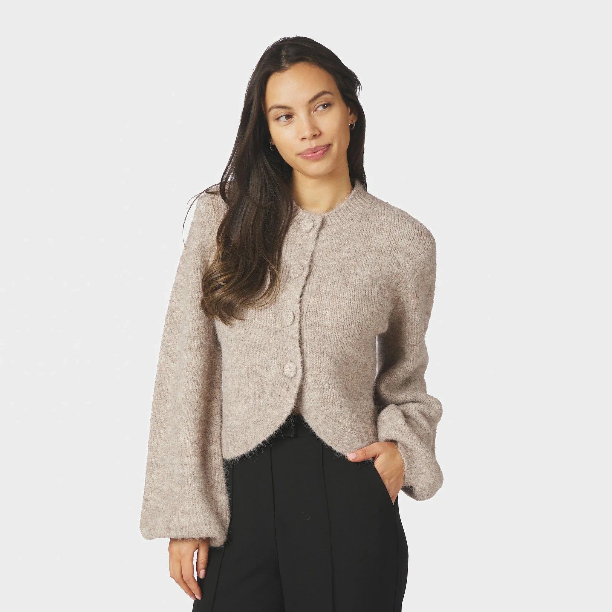 Model i beige fluffy cardigan med knapper foran og sorte bukser, set forfra