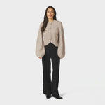 Model i hel figur med beige fluffy cardigan, sorte bukser og sorte støvler