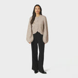 Model i hel figur med beige fluffy cardigan, sorte bukser og sorte støvler